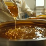 Honey pouring from a spoon into a pot in a modern factory